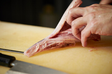 Hands cutting tuna with a knife
