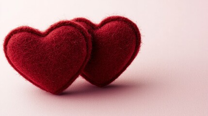 Fototapeta premium Two Soft Red Felt Hearts on a Light Pink Background for Love Themes