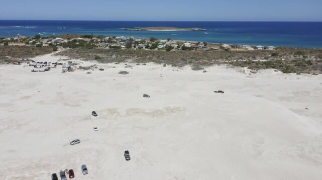 Aerial view of Lancelin sand dunes with cars driving and coastline, Western Australia