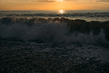 Fototapeta premium Powerful ocean waves crashing on the shore at sunset