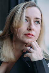 A blonde girl with red lips. A large portrait. Fingers under the chin, thoughtful look