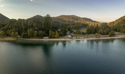 Lakefront park with cars, people relaxing, and enjoying the scenery. Peaceful day by the water. The Blue Lake, Rotorua, Bay Of Plenty, New Zealand