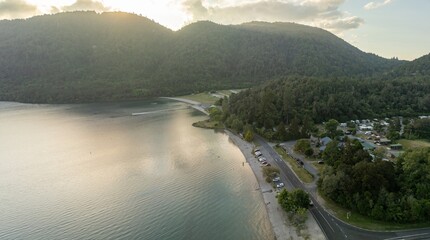 Aerial view of a lakefront campsite. Cars parked along the shore, campers in the background....