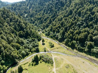 High-angle view of a meandering river flowing through lush green forest. A network of trails and open meadows are visible. Natural beauty. Ruatahuna, Te Urewera Forest, Bay Of Plenty, New Zealand