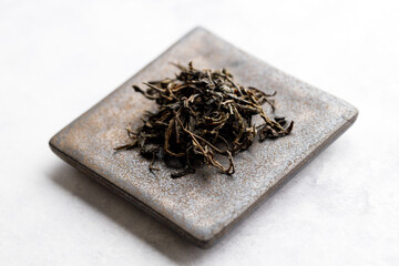 Japanese or Chinese jasmine tea leaf on black ceramic plate on white background.