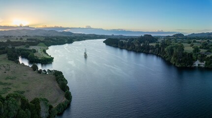 Aerial view of Waikato River, winding through farmland at sunset. A construction platform is in the middle of the river. Peaceful rural landscape. Karapiro, Waikato, New Zealand