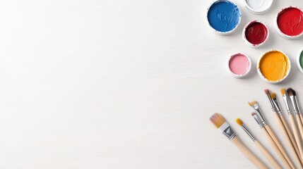 Naklejka premium Colorful paint containers and brushes on a white surface