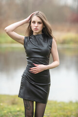 Portrait of a young beautiful brown-eyed long-haired girl in a black dress in nature.