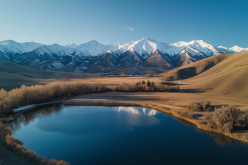 Fototapeta premium Peaceful lake surrounded by snow-capped mountains, offering a serene and picturesque winter landscape.