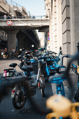 Obraz premium Urban Street Scene With Parked Electric Bicycles Under Highway Overpass