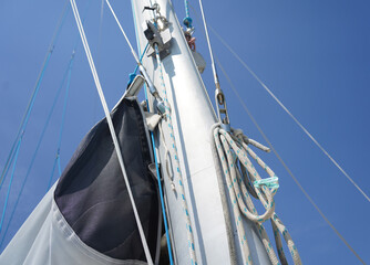 Tall sturdy mast of a sailboat stands out vividly against the bright blue sky.