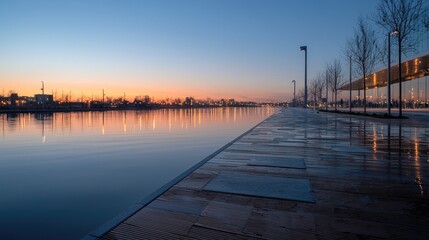 Obraz premium Calm waterfront at dawn, city skyline reflected in water, walkway