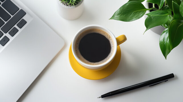 A white desk with black coffee, a notebook, and a pencil on it. There is also an open laptop computer next to the cup of hot coffee