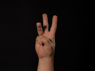 A hand is raised with three fingers extended