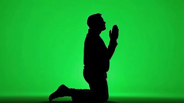 Silhouette of Man Praying on Knees against Green Background, loop, looping