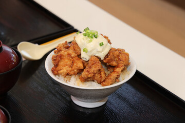 A delicious bowl of crispy fried chicken served over rice, topped with mayonnaise and green onions.
