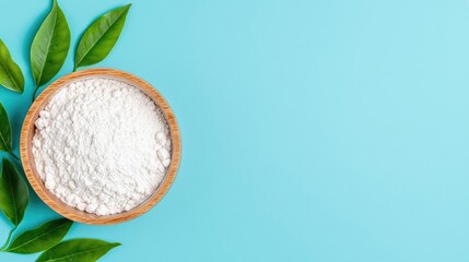 Wooden bowl of white powder with green leaves on a light blue background.  Possible use food product presentation