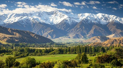 Fototapeta premium Snow-capped mountains towering over a lush green valley.