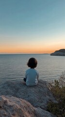 Fototapeta premium Child enjoying a serene moment by the ocean on a rocky cliff in summer sun