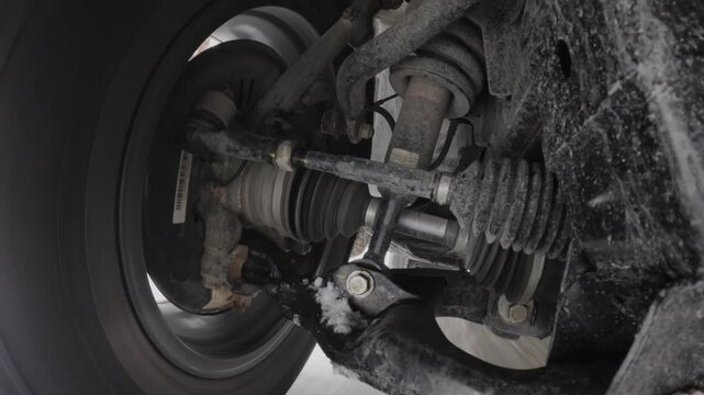 The operation of the car suspension in motion. Camera at the bottom of the car. The car is driving in the snow