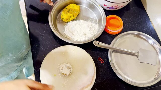 Woman shapes chapati from dough on the kitchen counter