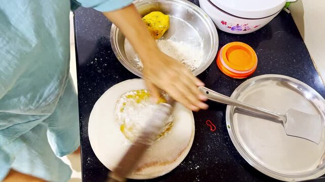 Lady using rolling pin to forms paratha for cooking