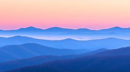Layers of mountains at sunrise reveal a beautiful hazy gradient in shades of pink and blue