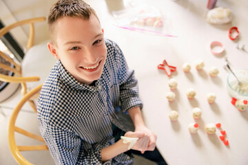 A happy teenage boy decorating valentine's treats