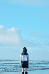 Fototapeta premium 青空と海を背景に立つ女子高校生