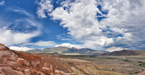 brown and red mountains under fine large clouds
