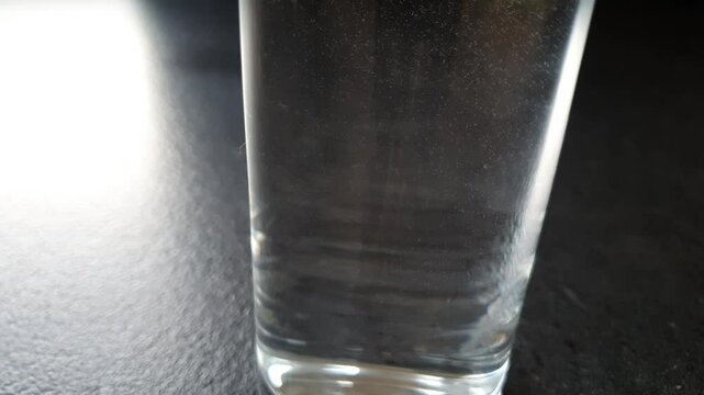 A glass filled with water and unidentified particles swirling inside.