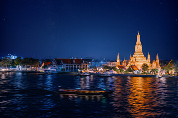 Beautiful night view of Wat Arun ratchawararam with stars, illuminated thai temple and river...