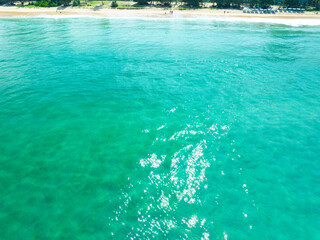 Fototapeta premium Aerial view of blue sea surface water texture background,Sun reflections on water, Aerial flying drone view Waves water surface texture on sunny tropical ocean in Phuket island Thailand