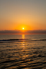 Beautiful sunrise over the sea, with golden reflections on water surface.