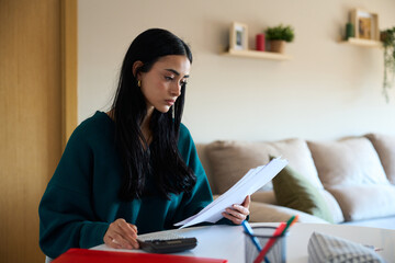 Young woman managing home finances and calculating expenses at home