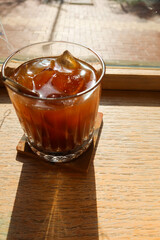 close up of iced black americano long black coffee on a wooden table by the window side with sunlight