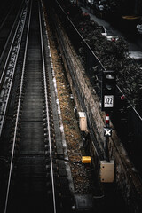 Fototapeta premium Dark and Moody Urban Railway Tracks with Signal Light and Weathered Infrastructure in a Rainy Cityscape