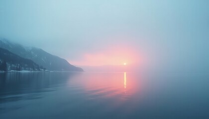 Fototapeta premium Misty Sunrise Over Calm Water, Mountains in Fog. Possible use Stock photo for nature, travel, or peaceful backgrounds