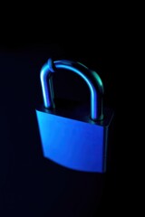 Fototapeta premium A close-up of a shiny padlock illuminated by blue light against a dark background, symbolizing security