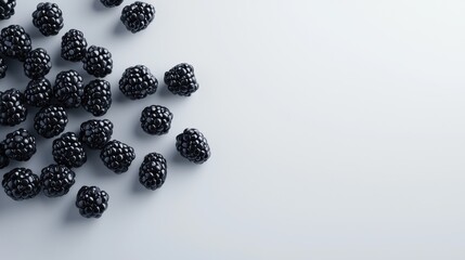 Group of small black berries scattered on a light blue background. the berries are arranged in a scattered manner, with some overlapping each other.