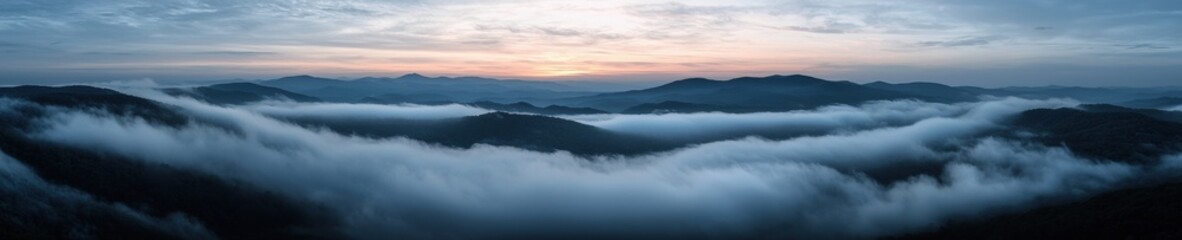Obraz premium Landscape photograph of a mountain range at sunset. the sky is filled with clouds and the sun is setting in the background, casting a warm orange glow over the mountains.