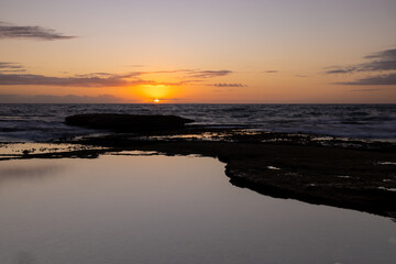 Beautiful sunrise with the sky reflecting in a rock pool along the coast of tamarama beach, Sydney, Australia