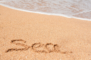  word Sea is written on the sand, a sea wave is running