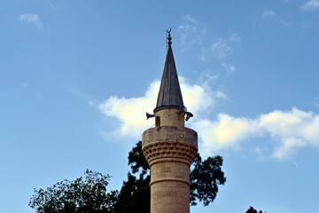 Minaret of the Merkez Adliye Mosque which is a popular tourist attraction in Bodrum. View from main street in downtown area near the marina and port. 