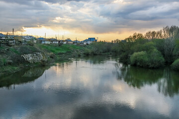 Fototapeta premium A river Ural in Russia with a reflection of the sky and houses on the other side