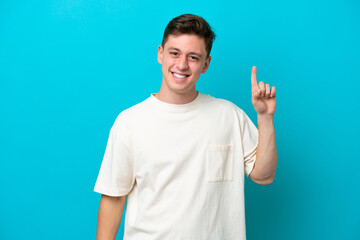 Fototapeta premium Young handsome Brazilian man isolated on blue background pointing up a great idea