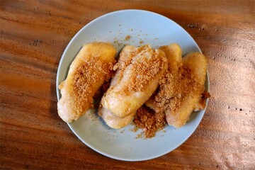 Pisang goreng gula aren in Indonesia or Fried bananas with palm sugar on a plate served on a wooden background.