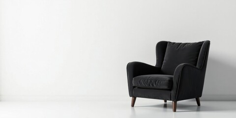 A dark upholstered armchair with wooden legs sits against a minimalist white wall in a modern interior setting
