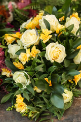 Yellow funeral flowers on the grave. A beautiful memorial bouquet at the cemetery. The flowers are pale yellow, almost white roses and yellow freesia.