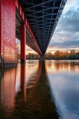 Bridge with a reflection at sunset over calm waters.